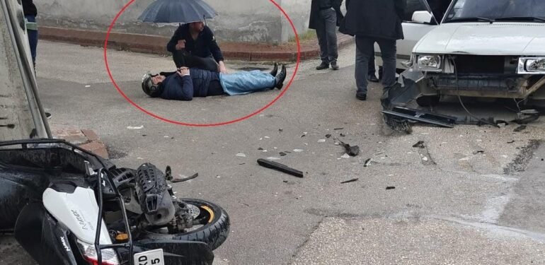 Kazada yaralanan motosikletli ıslanmasın diye şemsiyeyle başında bekledi